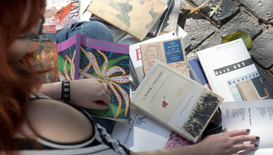 Student staring at books published by BGSU alumni, staff and professors